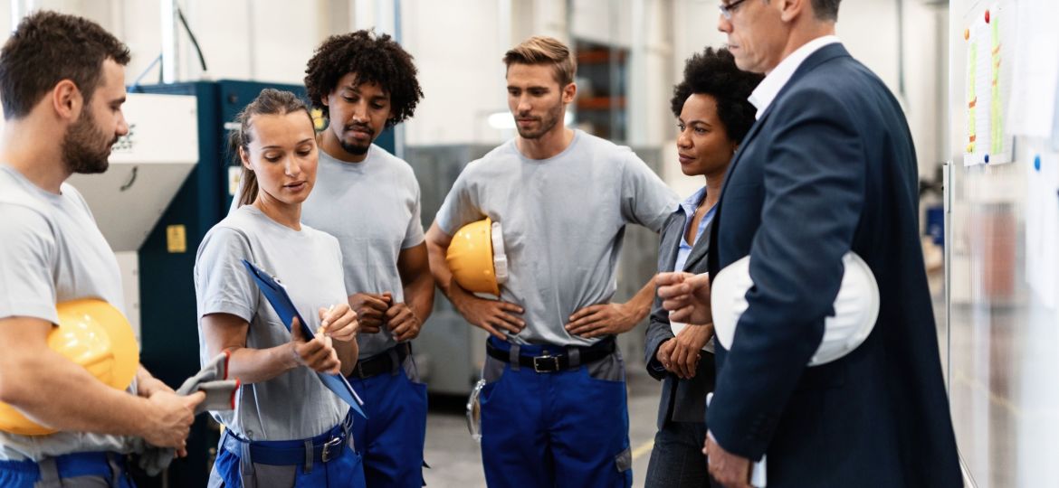 Female worker showing production reports to company managers in a factory.